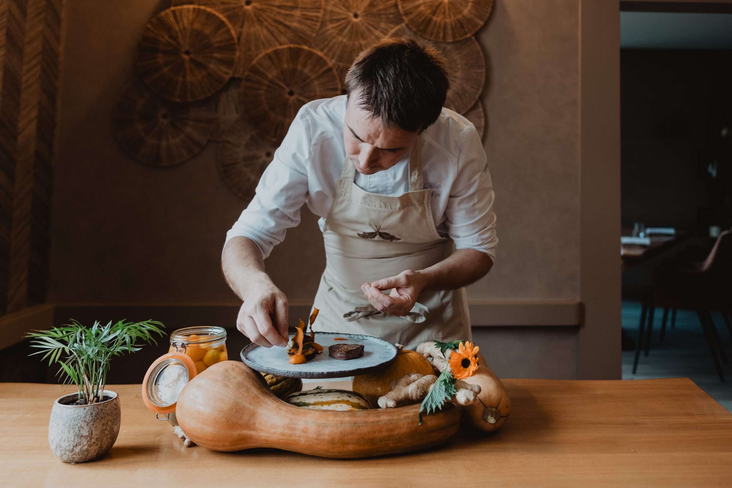 Assiette de nourriture gastronomique avec un verre de vin blanc, sur fond noir, présentant une esthétique raffinée.
